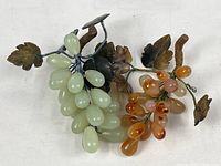 Both carved-stone grape clusters showing color contrast and leaf detail