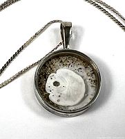 Pendant close-up showing sand dollar encased in sand within silver bezel