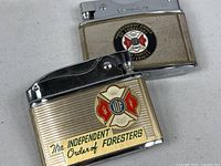 Two Brother-Lite lighters showing fronts with IOF crests