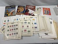 Three albums and stack of filled U.S. stamp pages spread on table