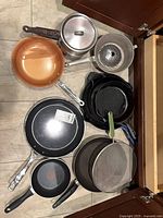 Overview of mixed cookware items inside cabinet