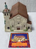 Front view of ceramic mission figurine with information card