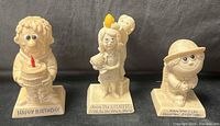 front view of all three resin figurines displaying slogans