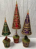 Group shot of four jeweled cone Christmas trees showing colors, sizes and pedestal bases