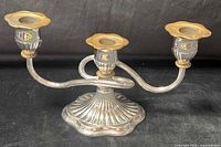 Front view of three-arm silver-tone metal candelabra showing overall design and gold-tone accents