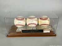 Front view of three signed baseballs in acrylic display with plaque visible