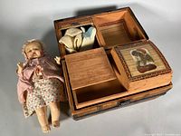 Doll, open wooden trunk with compartments and clothing pieces