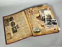 Open scrapbook displaying mixed newspaper clippings, photographs and ephemera