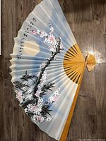 Full view of unfolded fan showing artwork, ribs and size