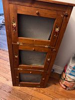 Front view of cabinet showing three mesh doors and painted floral accents