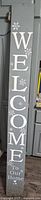 Grey side of reversible barn board sign showing “Welcome to our home” text