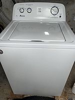 Front view of white Amana top-load washing machine showing control panel and overall condition