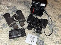 Camera and three binoculars arranged on surface