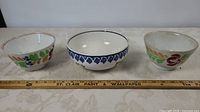 Front view of three ceramic bowls with ruler for scale