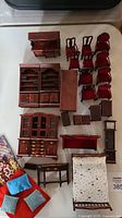 Overall view of lot: multiple wooden miniature furniture pieces, bedding visible