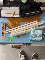 Rulers, drafting triangles, boxed pens, bag of batteries visible