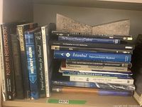 Books standing and stacked on shelf with stone bookends visible