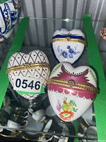 Three ceramic heart trinket boxes on glass shelf