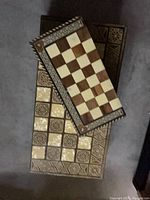 Two closed inlaid folding boards showing exterior chess grids and decorative borders