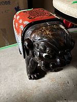 Front and side view of carved wooden dog stool showing head detailing and lacquer finish