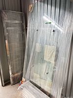 Wrapped glass tabletop and metal frame components leaning against wall