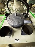 Top view of cast iron teapot with four matching cups on table