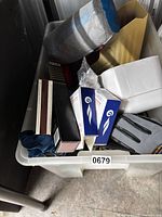 Overview of bin showing eyeglass boxes, camping mat, gloves, match boxes, yellow holder