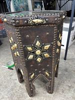 Full view of leather-wrapped side table showing stud and inlay decoration on sides and leg cutouts