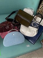 Group of six handbags and jewelry case on chair