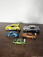 All five die-cast cars displayed on tabletop, variety of colours and designs visible