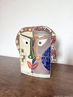 Front view of cubist ceramic face vase showing multicolored glazed design