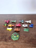 All 13 miniature Transformers figures laid out on wood surface