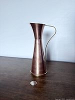 Full view of copper brass pitcher vase beside coin for scale