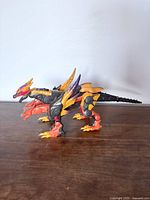 Left side profile of three-headed hydra dragon figure showing colors and form