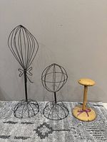 All three hat stands side by side on rug against wall