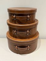 Three stacked brown faux-leather nesting hat boxes
