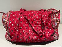 Full view of red quilted Vera Bradley weekender bag showing handles and overall pattern