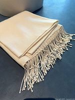 folded light cream shawl showing fringe detail