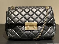 Front view showing quilted leather, gold clasp and chain strap