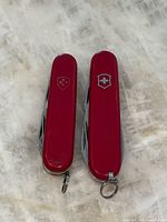 Front view of both closed red Victorinox knives side by side