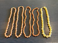Full view of all five bead necklaces laid flat