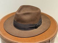 Full view of brown felt fedora on hat box, showing crown and brim