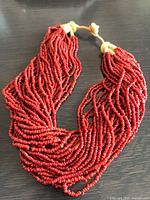 Full view of multi-strand red coral bead necklace laid flat