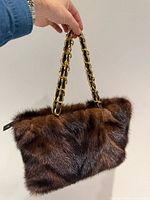 Front view of dark brown mink fur handbag showing twin gold-tone chain and leather handles