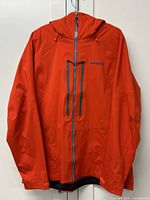 Front view of red Patagonia Stormstride jacket hung on hanger