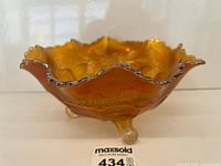 Side view showing marigold iridescence, ruffled rim, and three clear feet