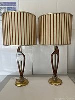 Front view showing both lamps, teak bodies, brass bases, striped shades