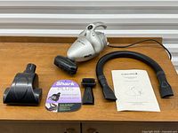Lot overview: vacuum, hose, attachments, literature and manual displayed on table