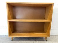 Front view of blonde wood two-tier bookshelf on legs