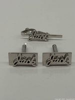 Pair of chrome cufflinks and tie clip with Jack script